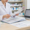 薬価基準収載リストと後発医薬品情報を薬局のデスクで整理する薬剤師