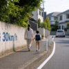中央線のない住宅地の道路を歩く親子と、生活道路30km/hの案内文字