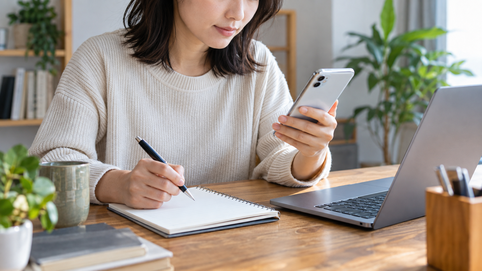 スマートフォンとノートを使い、登録済みの連絡先を整理する様子